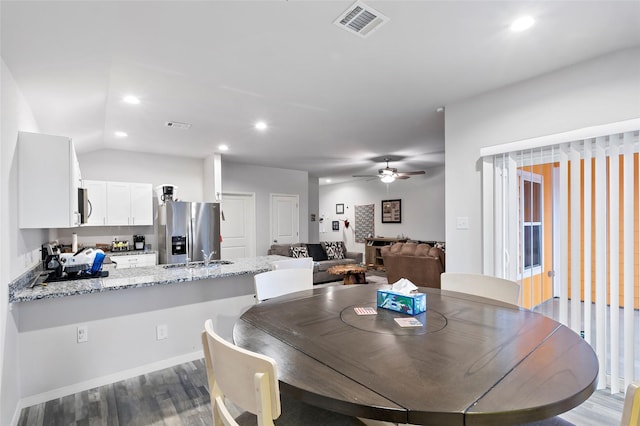 dining space with ceiling fan, sink, vaulted ceiling, and hardwood / wood-style flooring