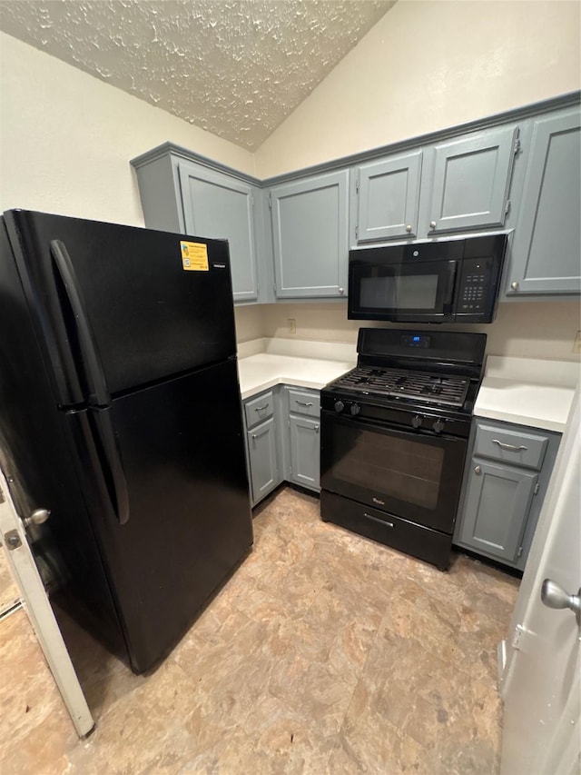 kitchen featuring a textured ceiling, gray cabinets, black appliances, and lofted ceiling