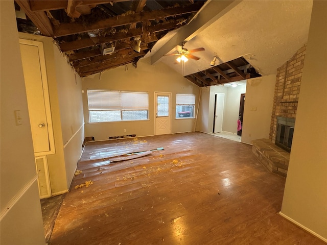 unfurnished living room featuring vaulted ceiling with beams, ceiling fan, a fireplace, and wood-type flooring