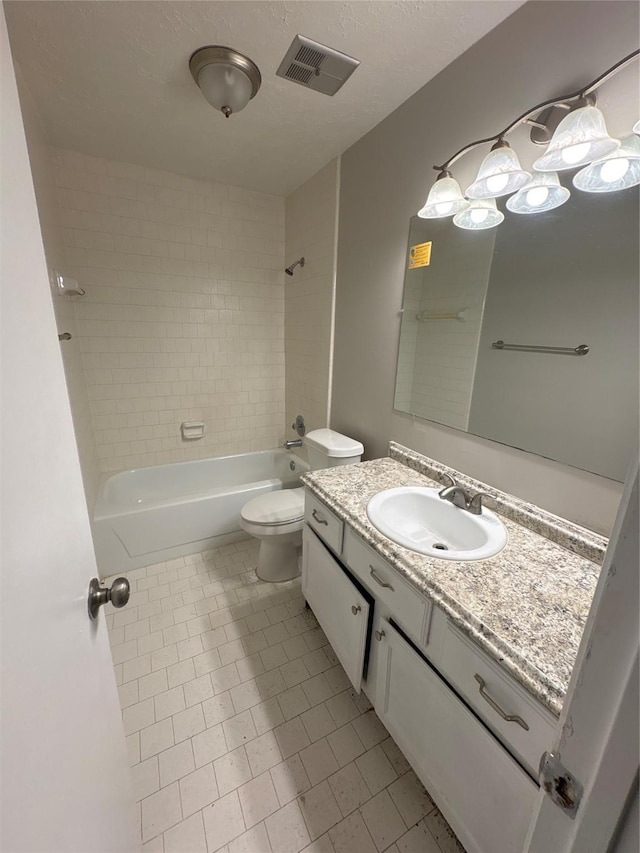 full bathroom with vanity, tile patterned floors, tiled shower / bath, toilet, and a textured ceiling