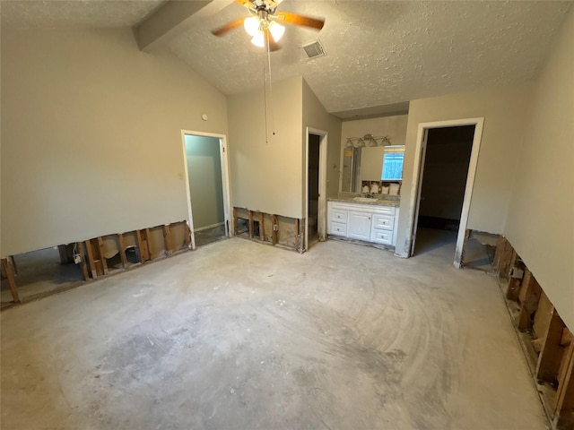 unfurnished bedroom featuring lofted ceiling with beams, ceiling fan, a walk in closet, and a textured ceiling