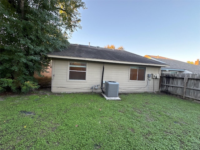 rear view of house featuring a lawn and cooling unit