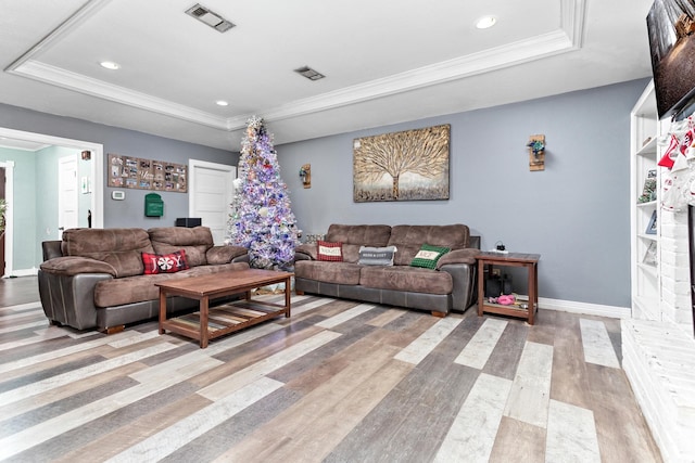 living room with hardwood / wood-style flooring, ornamental molding, and a tray ceiling