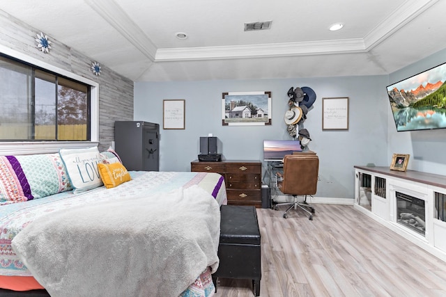 bedroom with light hardwood / wood-style floors, ornamental molding, and a tray ceiling