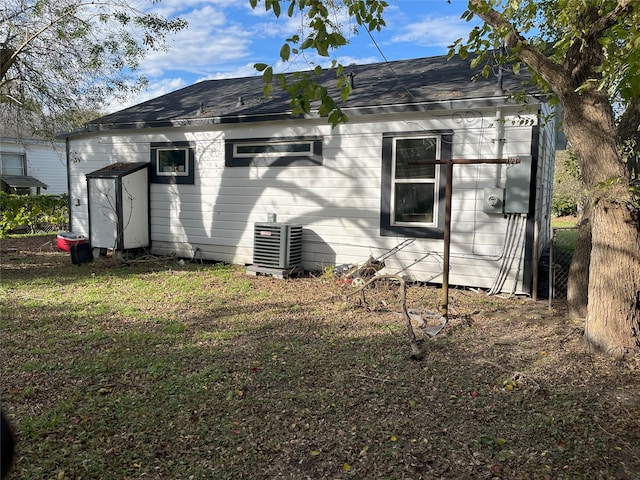 back of property with a shingled roof, fence, and central AC unit