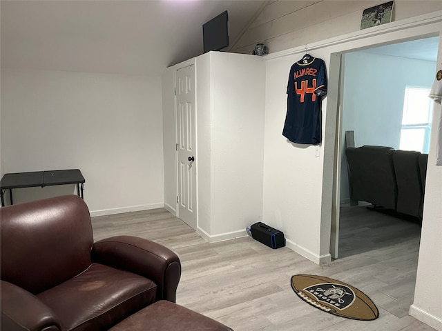 sitting room with lofted ceiling, light wood-style flooring, and baseboards