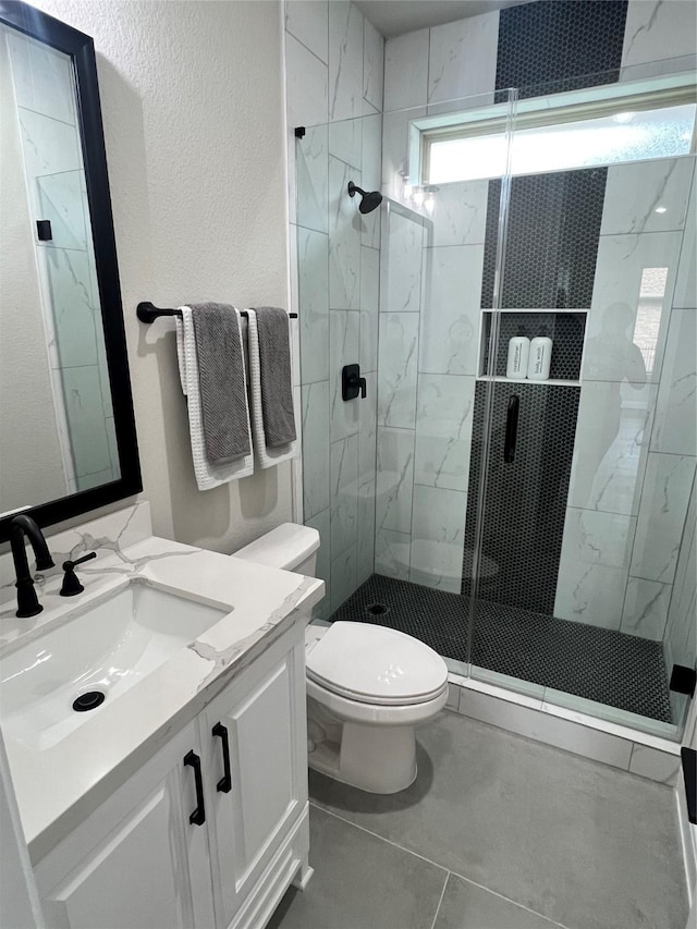 bathroom with toilet, vanity, tile patterned floors, and walk in shower