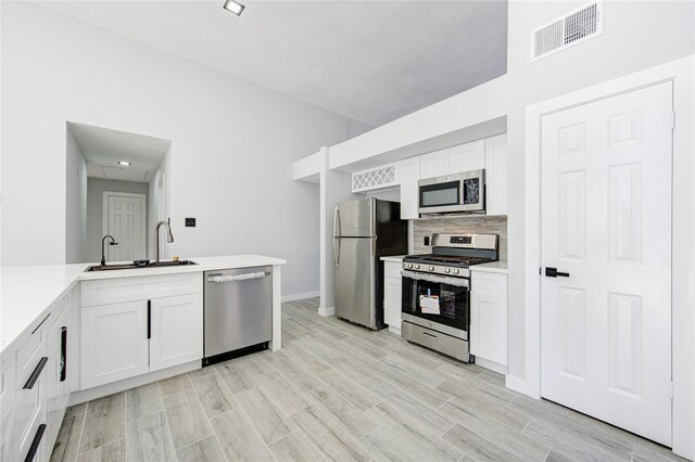 kitchen featuring backsplash, sink, light hardwood / wood-style flooring, appliances with stainless steel finishes, and white cabinetry