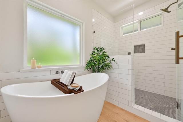 bathroom with separate shower and tub, a wealth of natural light, and hardwood / wood-style flooring