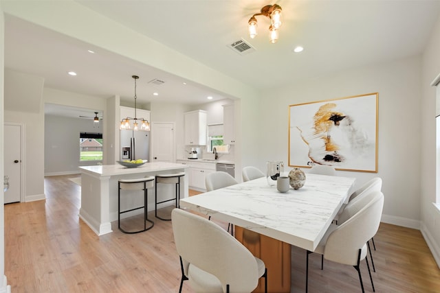 dining room with light wood-type flooring, ceiling fan, and sink