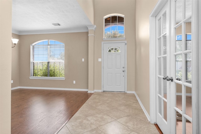 entryway featuring crown molding, french doors, a textured ceiling, and light wood-type flooring