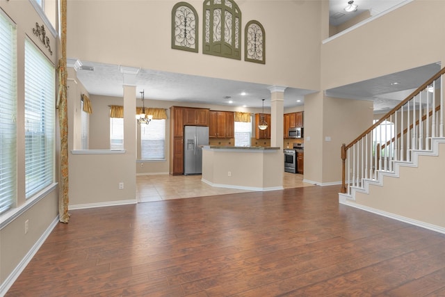 unfurnished living room featuring a chandelier, a towering ceiling, and light hardwood / wood-style flooring