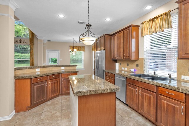 kitchen with sink, tasteful backsplash, decorative light fixtures, a kitchen island, and appliances with stainless steel finishes