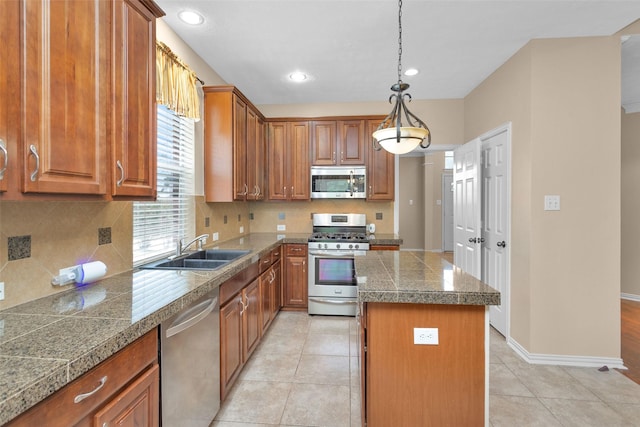 kitchen with a center island, sink, stainless steel appliances, pendant lighting, and light tile patterned flooring