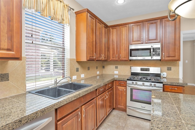 kitchen featuring decorative backsplash, sink, light tile patterned floors, and stainless steel appliances