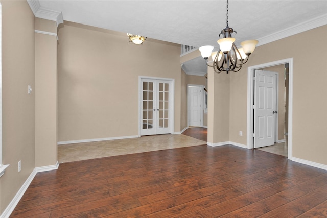 spare room with french doors, ornamental molding, dark wood-type flooring, and a notable chandelier