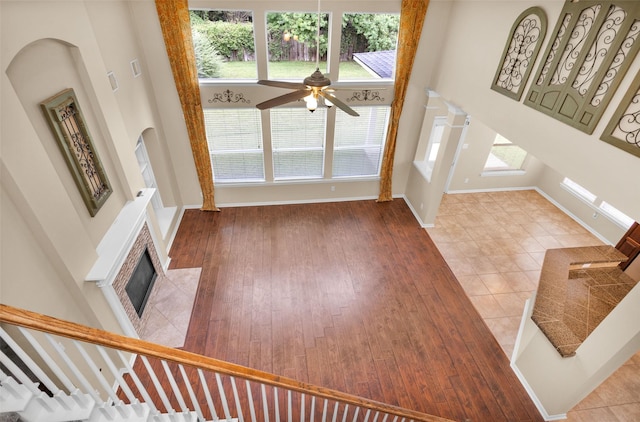 unfurnished living room featuring hardwood / wood-style floors, ceiling fan, and a high ceiling