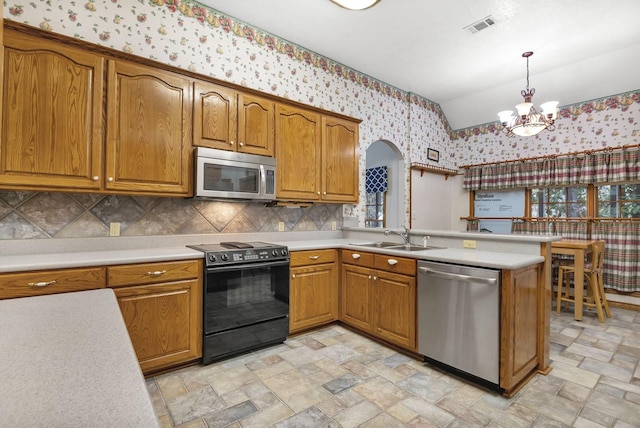 kitchen featuring appliances with stainless steel finishes, vaulted ceiling, sink, a chandelier, and hanging light fixtures