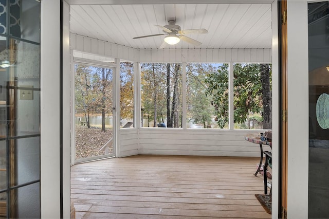 unfurnished sunroom with a wealth of natural light, a water view, wooden ceiling, and ceiling fan