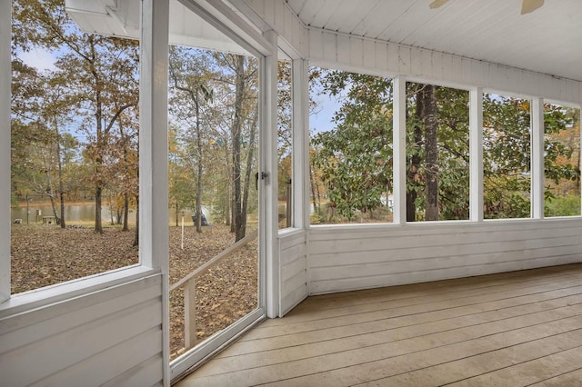 unfurnished sunroom with a water view, a wealth of natural light, and ceiling fan