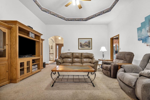 living room with carpet floors, a tray ceiling, and ceiling fan