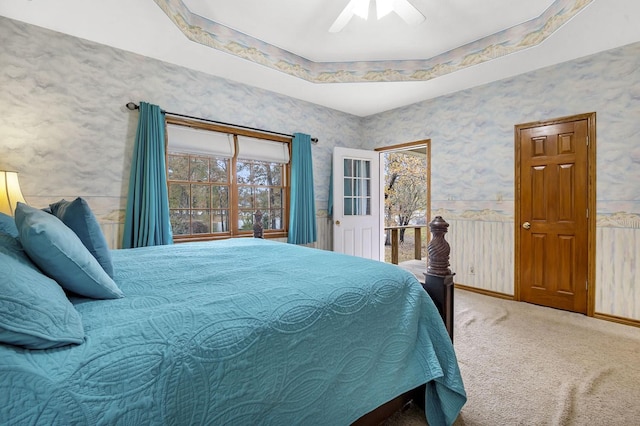 carpeted bedroom with ceiling fan and a tray ceiling