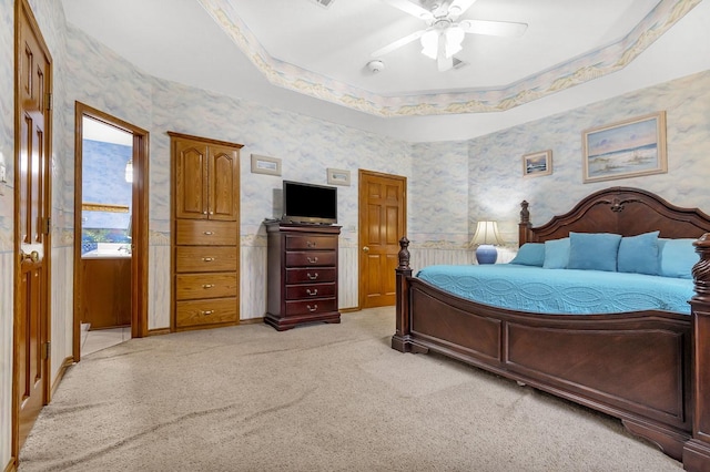 bedroom with a raised ceiling, ceiling fan, and light colored carpet