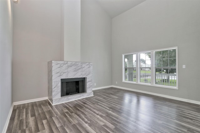 unfurnished living room featuring a fireplace, dark hardwood / wood-style flooring, and high vaulted ceiling