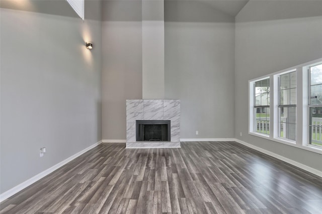 unfurnished living room with dark hardwood / wood-style floors, a premium fireplace, and high vaulted ceiling