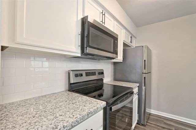 kitchen with dark wood-type flooring, stainless steel appliances, light stone counters, decorative backsplash, and white cabinets