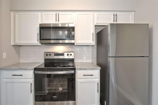 kitchen with white cabinets, decorative backsplash, light stone countertops, and stainless steel appliances