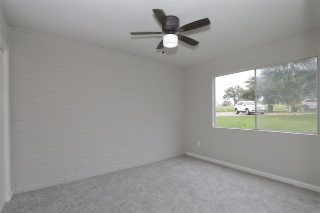 spare room with light carpet, ceiling fan, and brick wall