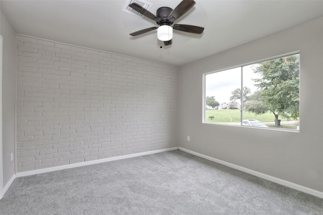 unfurnished room featuring carpet flooring, ceiling fan, and brick wall