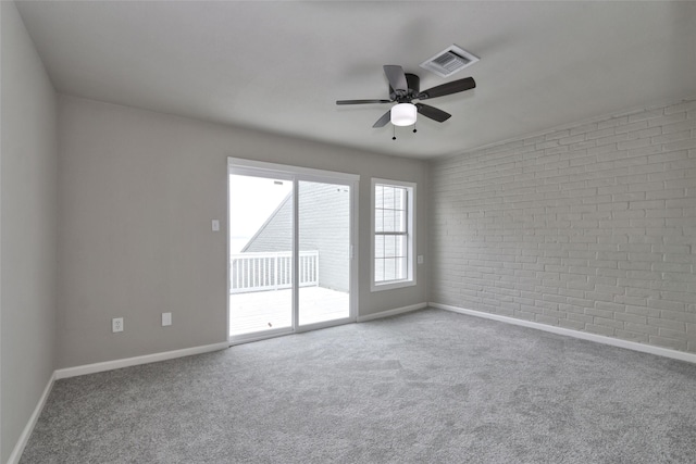 empty room with carpet floors, ceiling fan, and brick wall