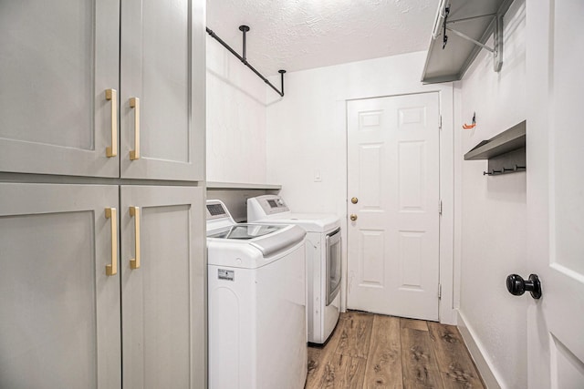 laundry room featuring cabinets, hardwood / wood-style floors, washer and dryer, and a textured ceiling