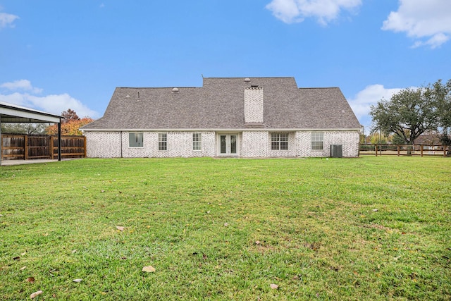 back of property with a lawn and central AC