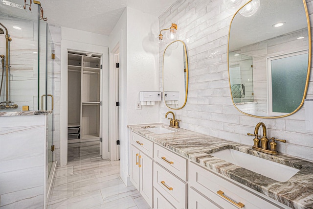 bathroom with a shower with door, vanity, and a textured ceiling