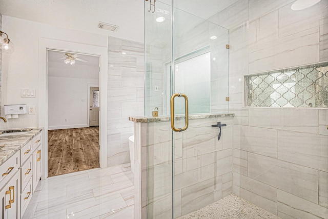 bathroom with vanity, hardwood / wood-style flooring, an enclosed shower, and ceiling fan