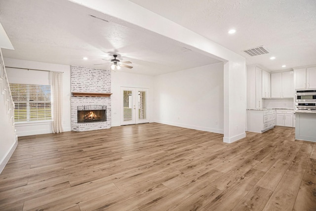 unfurnished living room with light hardwood / wood-style floors, a wealth of natural light, and ceiling fan