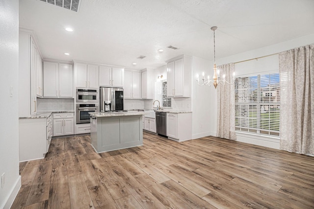 kitchen featuring white cabinets, appliances with stainless steel finishes, a center island, and light hardwood / wood-style floors