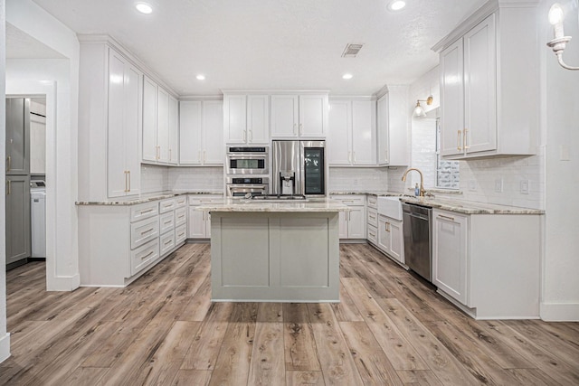 kitchen with light hardwood / wood-style flooring, white cabinets, and appliances with stainless steel finishes