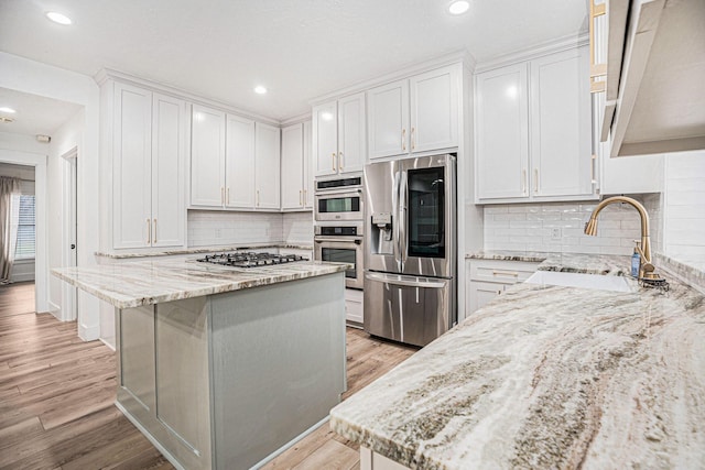 kitchen with light stone counters, white cabinetry, and appliances with stainless steel finishes