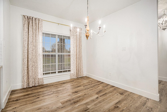 unfurnished dining area featuring a notable chandelier and hardwood / wood-style flooring