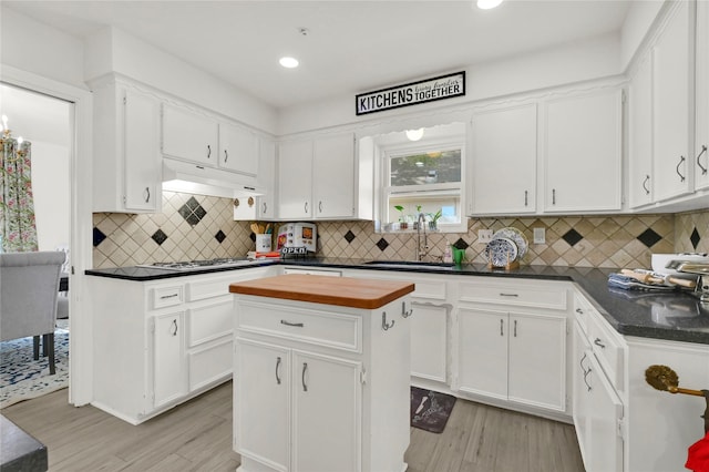 kitchen with white cabinetry, a center island, sink, tasteful backsplash, and light hardwood / wood-style flooring