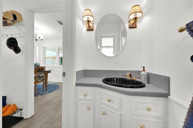 bathroom with vanity, hardwood / wood-style flooring, and an inviting chandelier