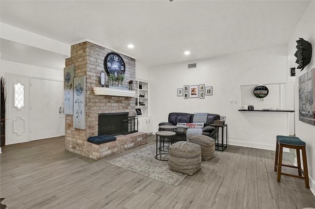 living room featuring a fireplace, hardwood / wood-style floors, and built in shelves