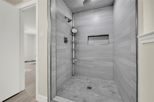 bathroom featuring a tile shower and wood-type flooring