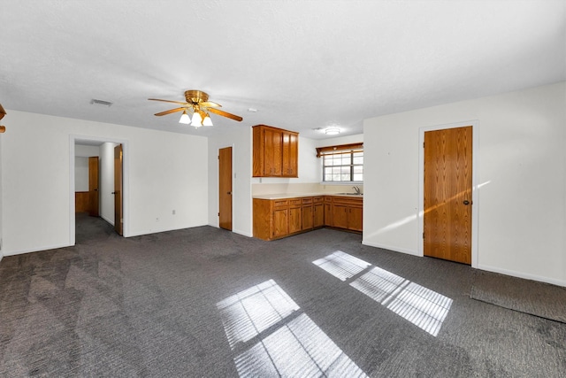 unfurnished living room with sink, dark carpet, and ceiling fan