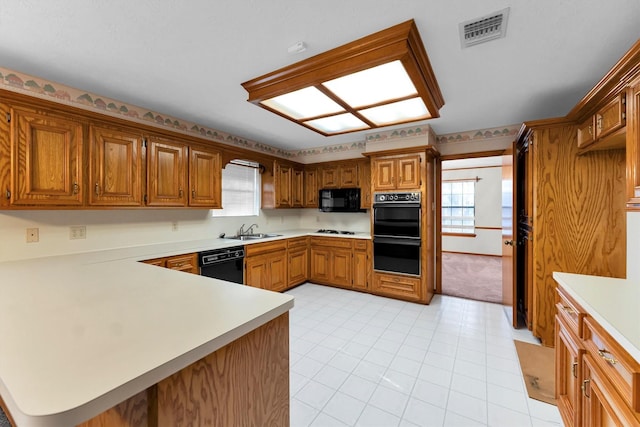 kitchen featuring sink, kitchen peninsula, and black appliances