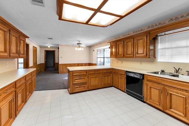 kitchen with sink, wooden walls, black dishwasher, kitchen peninsula, and ceiling fan